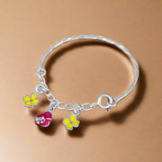 A silver bracelet featuring a chain-link design with two floral charms and a heart-shaped charm.